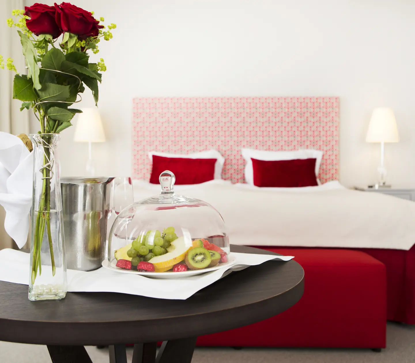 Bright suite with double bed, red textiles and vip on table in front