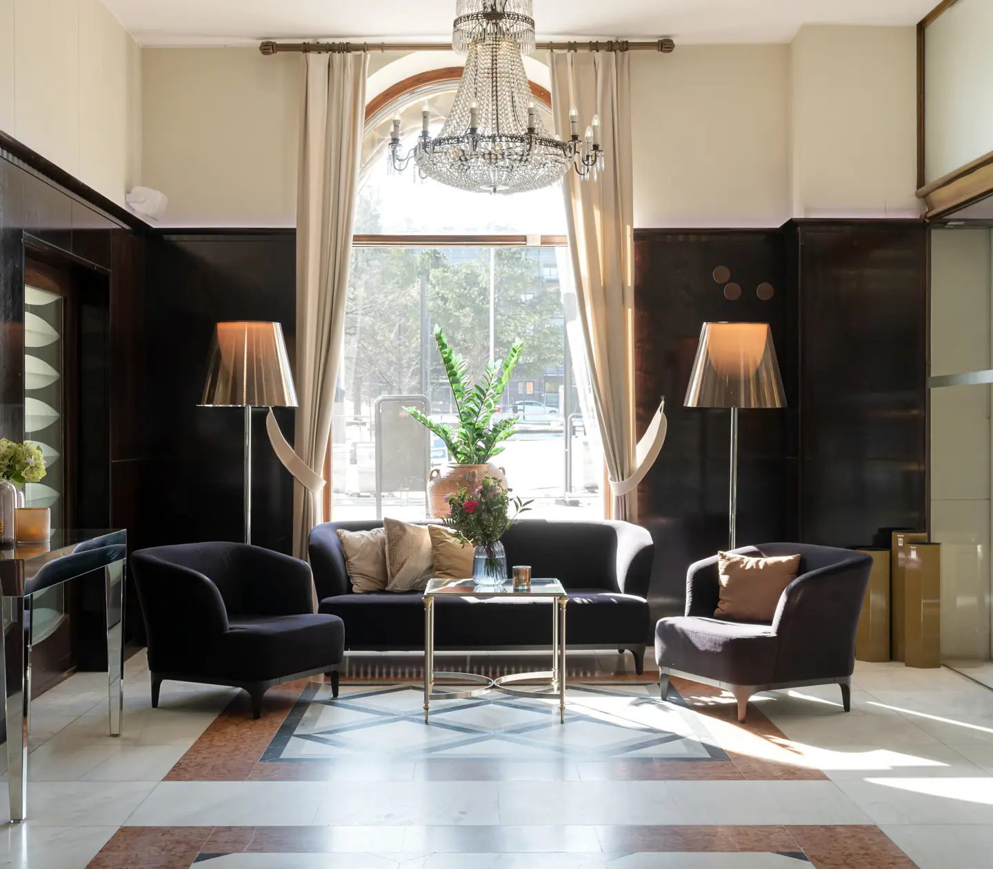 Hotel lobby with seating area, crystal chandelier and large window