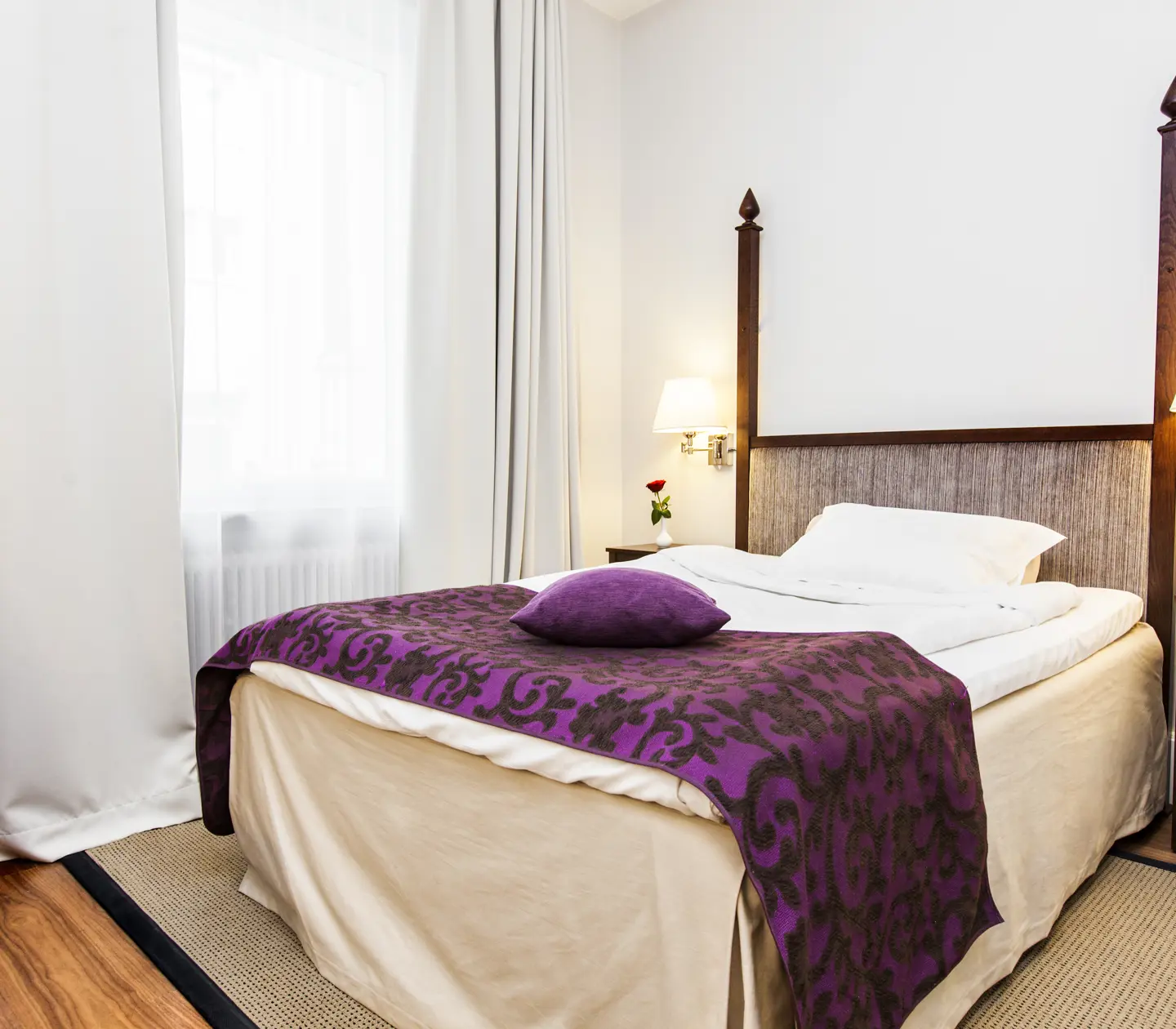 Bright hotel room with window, single bed and bedside lamps