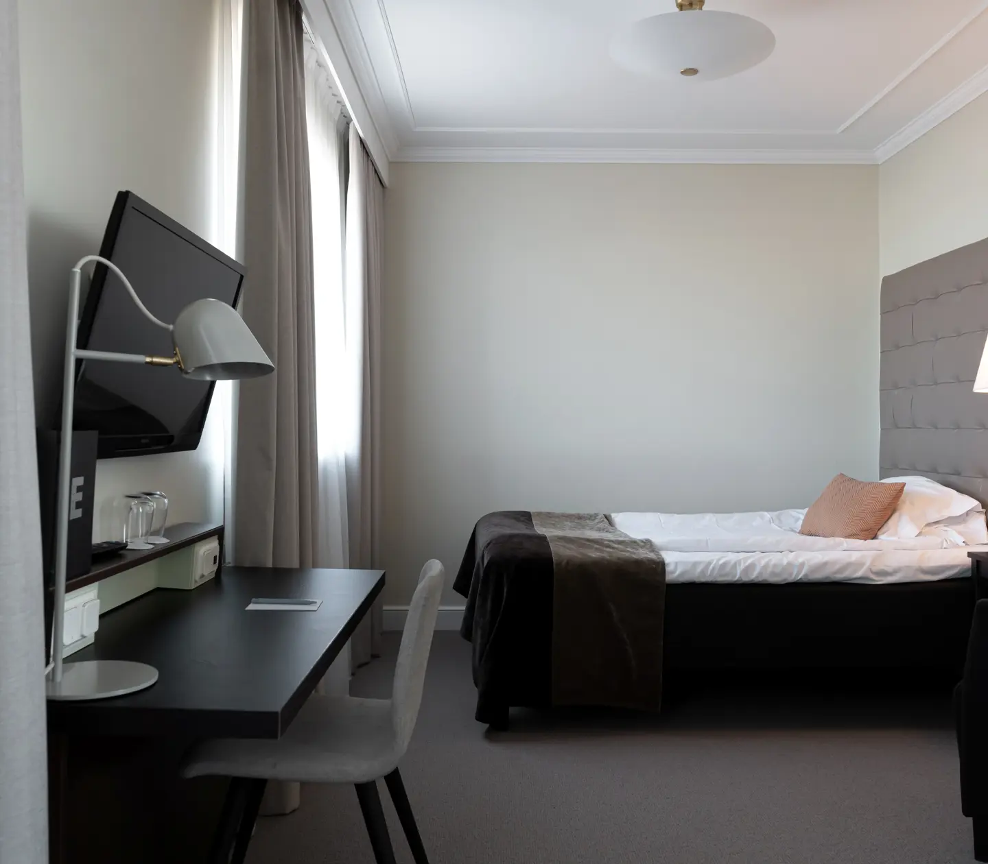 Bright hotel room with desk, bed and bedside lamp