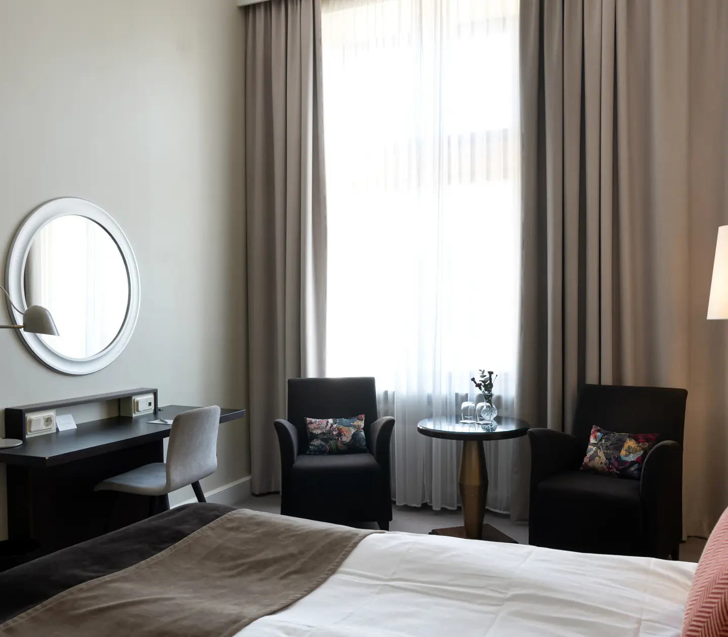 Bright hotel room with desk, armchairs and window