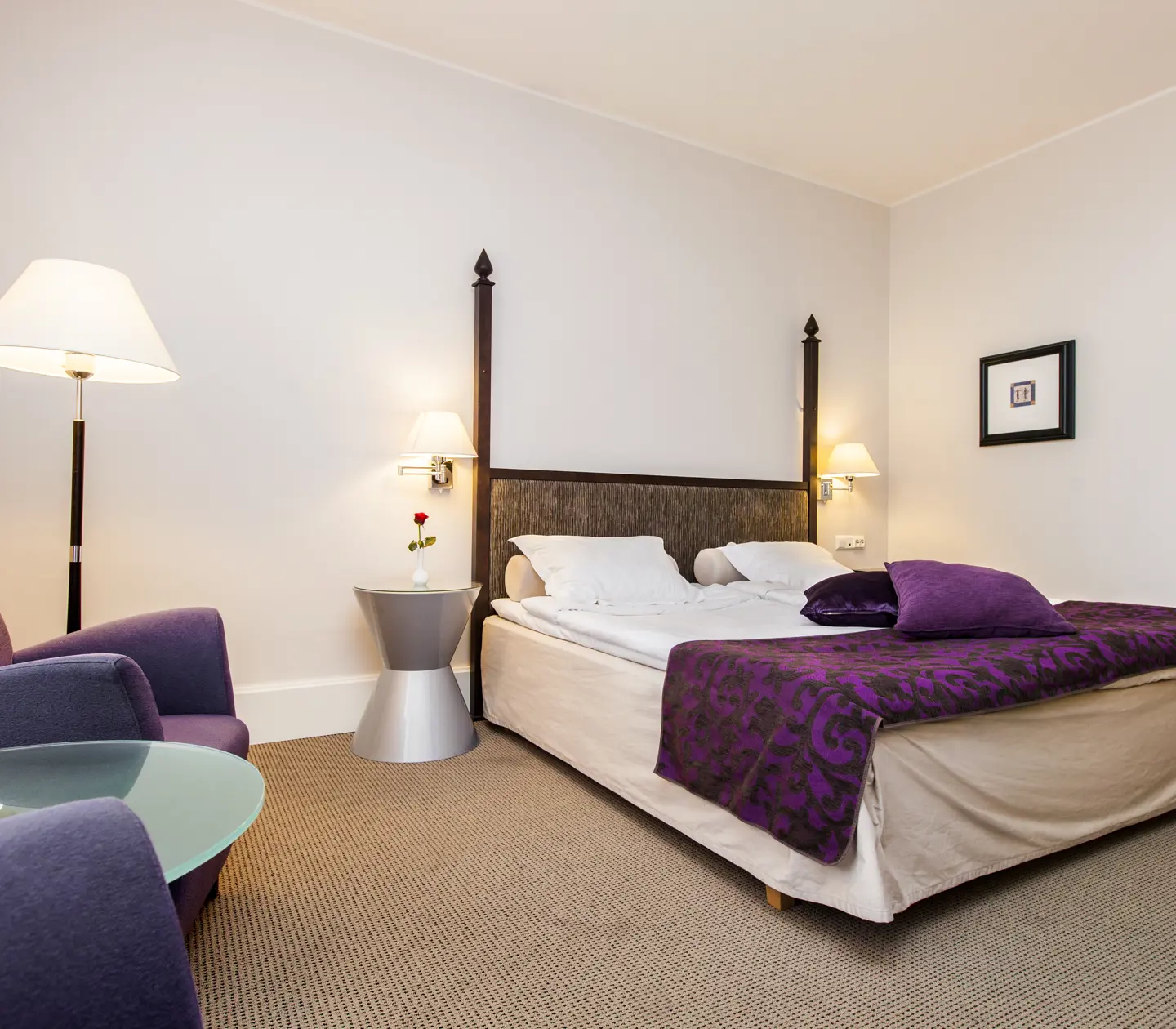Bright hotel room with bed, armchairs and floor lamp
