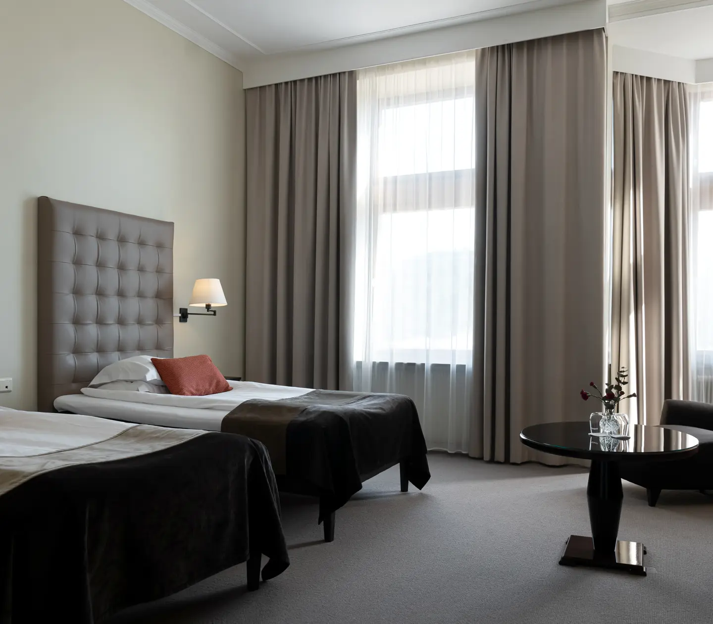 Bright hotel room with two single beds, sitting area and large windows