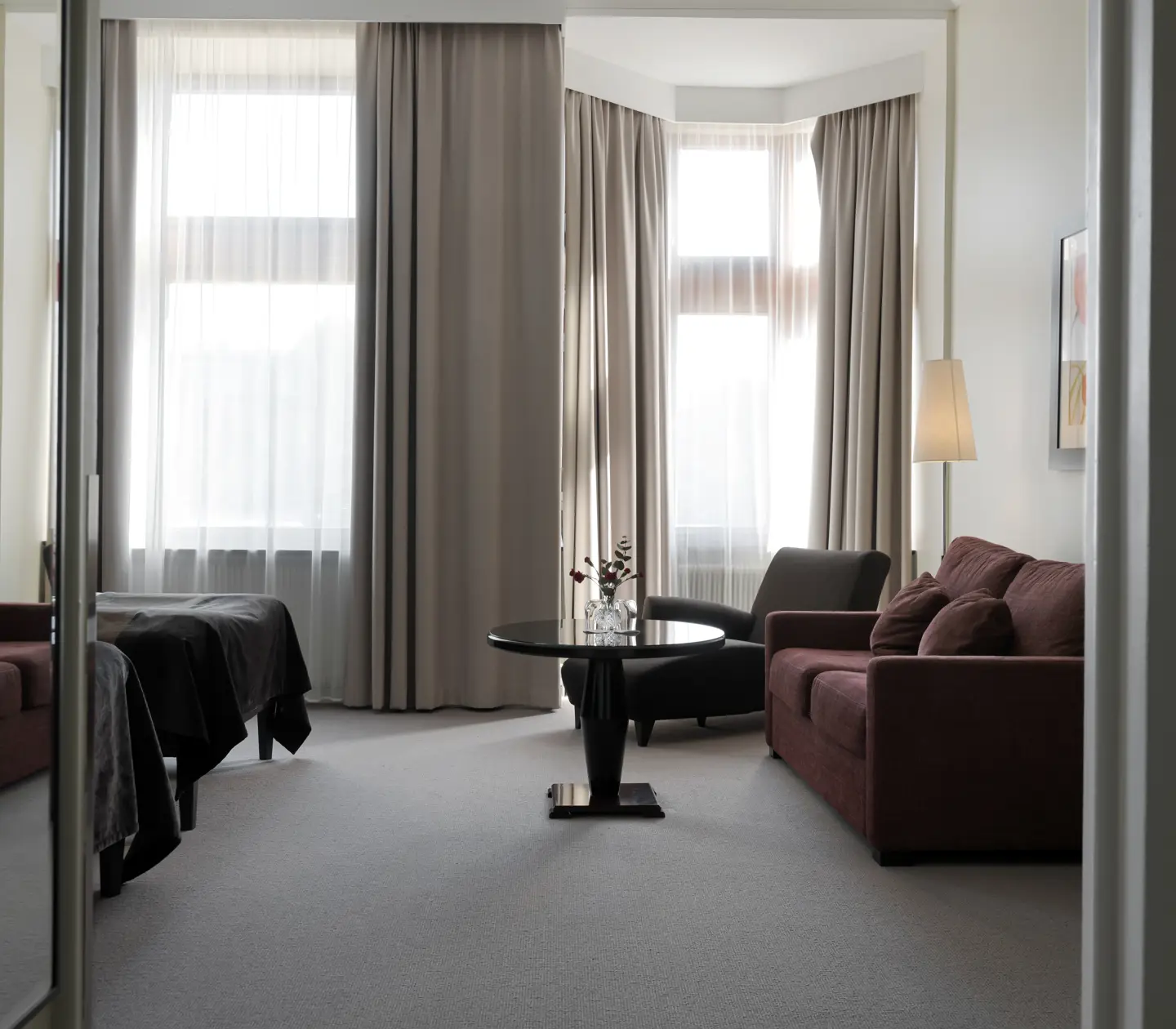 Bright hotel room with sitting area, window and mirror