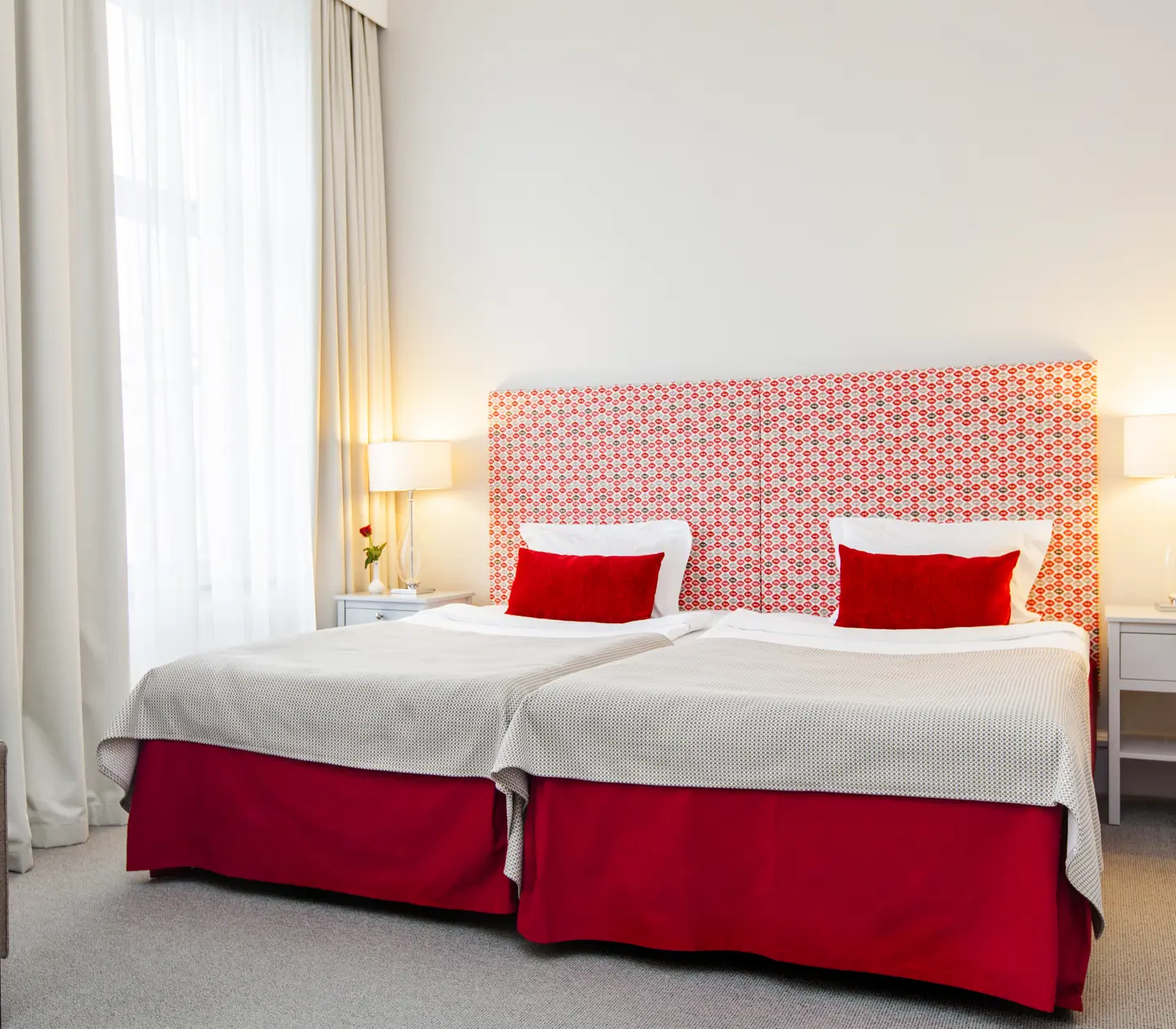 Bright hotel room with bed, red headboard and armchair