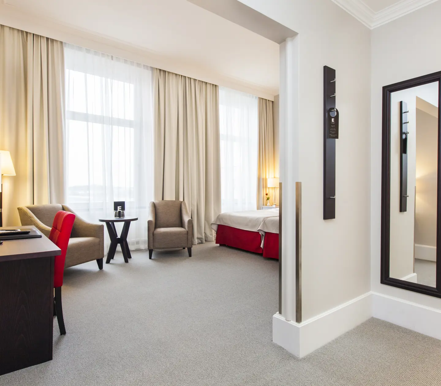 Bright hotel room with desk, armchairs and window