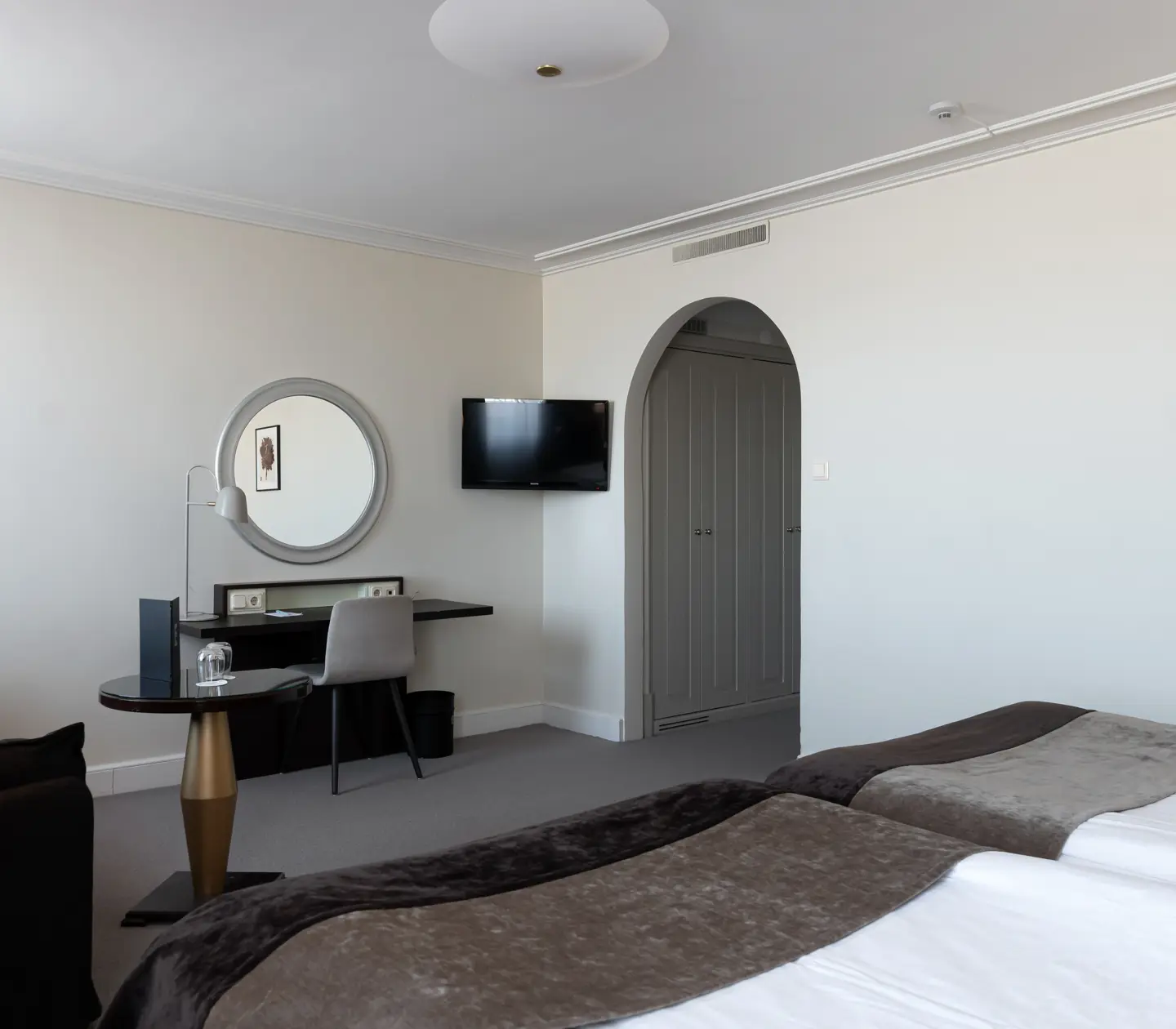 Bright hotel room with vault, desk and round mirror