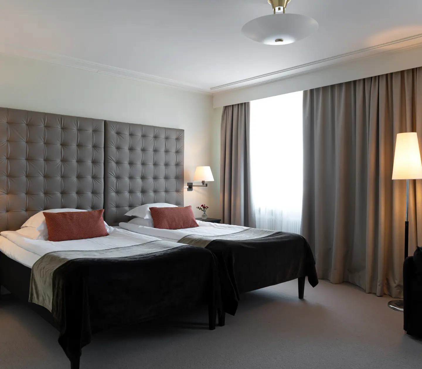 Bright hotel room with bed, large headboard and curtains