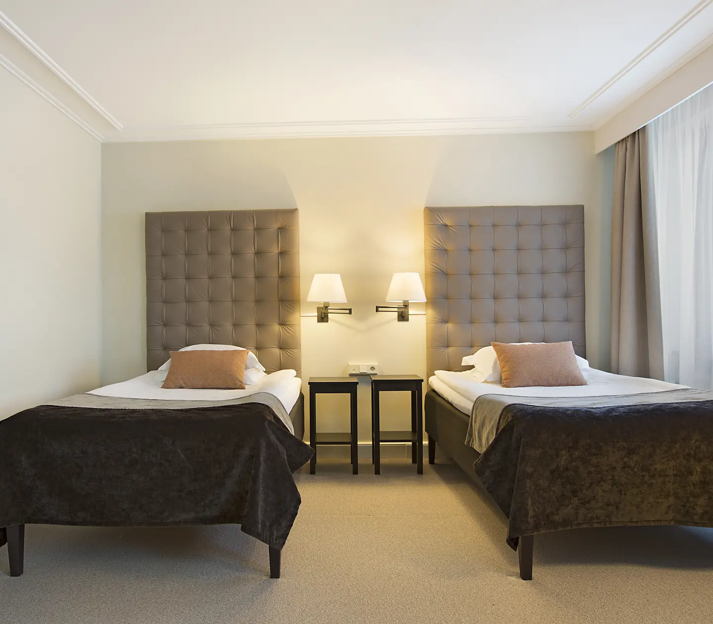 Bright hotel room with two beds, bedside tables and bedside lamps
