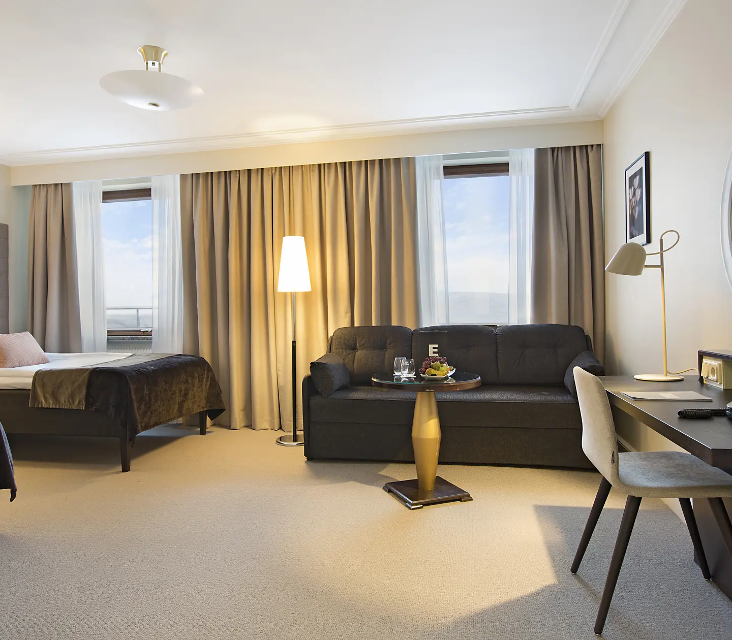 Bright hotel room with two beds, sofa and desk