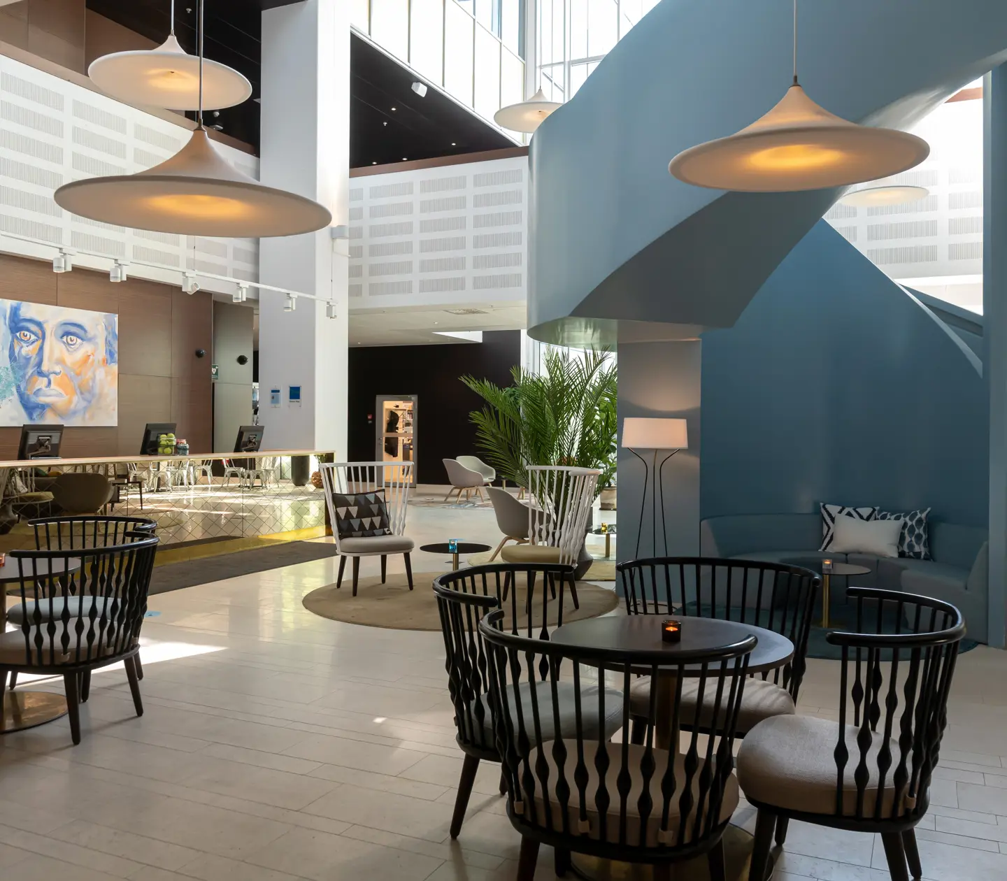Hotel lobby with reception desk, many dining areas and blue staircase