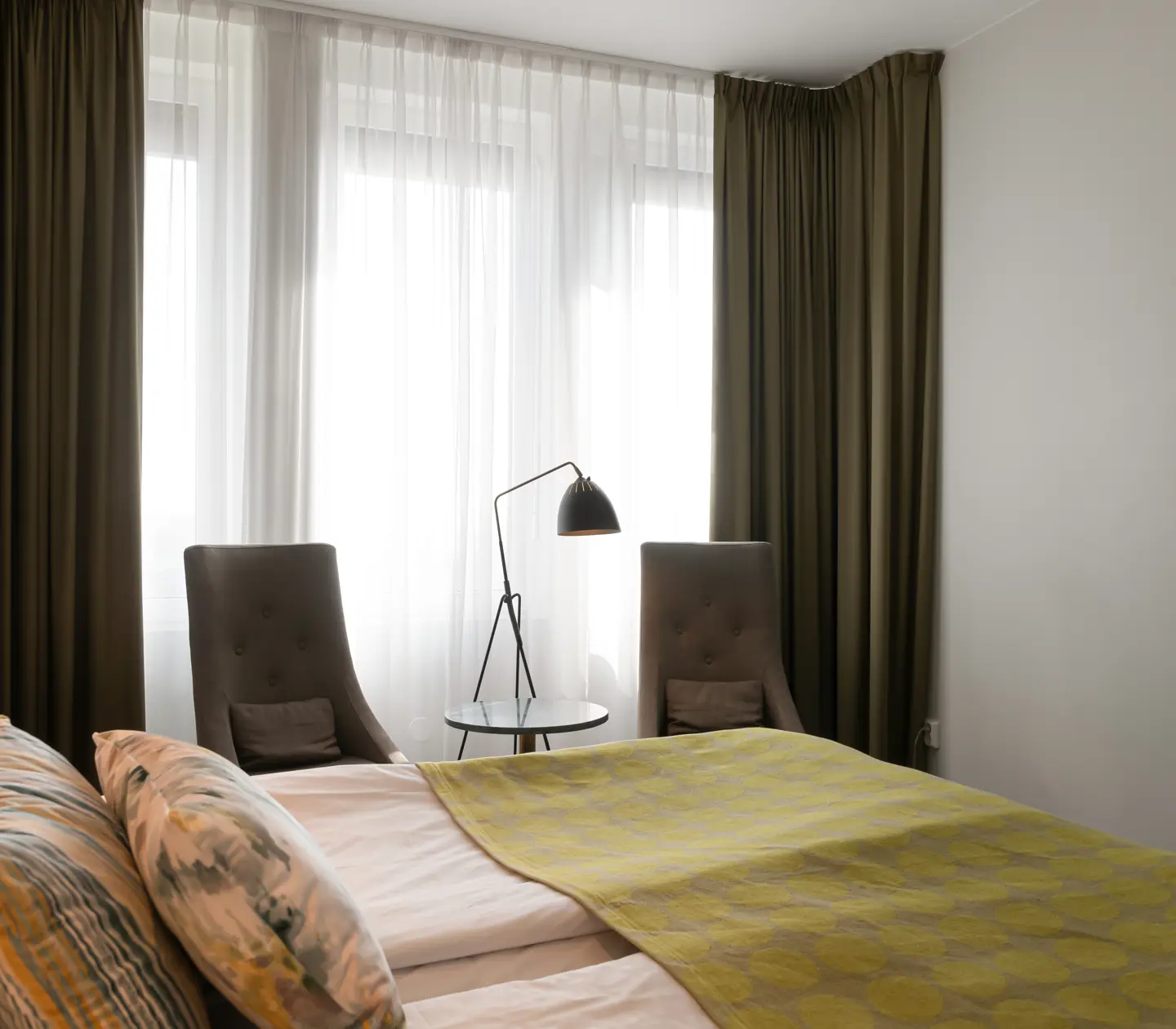 Hotel room with bed, armchair and curtains