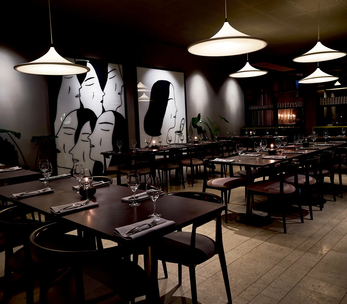 Restaurant environment with dining groups, lamps and large paintings