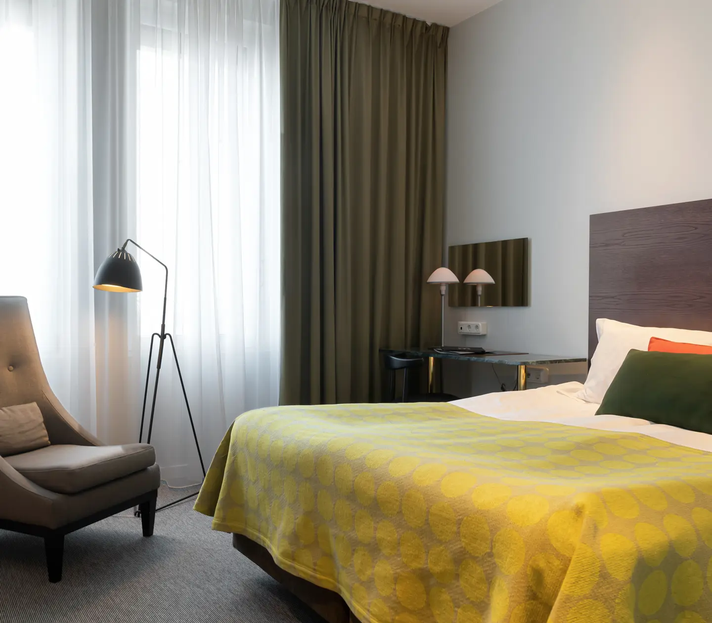 Bright hotel room with bed, armchair and window