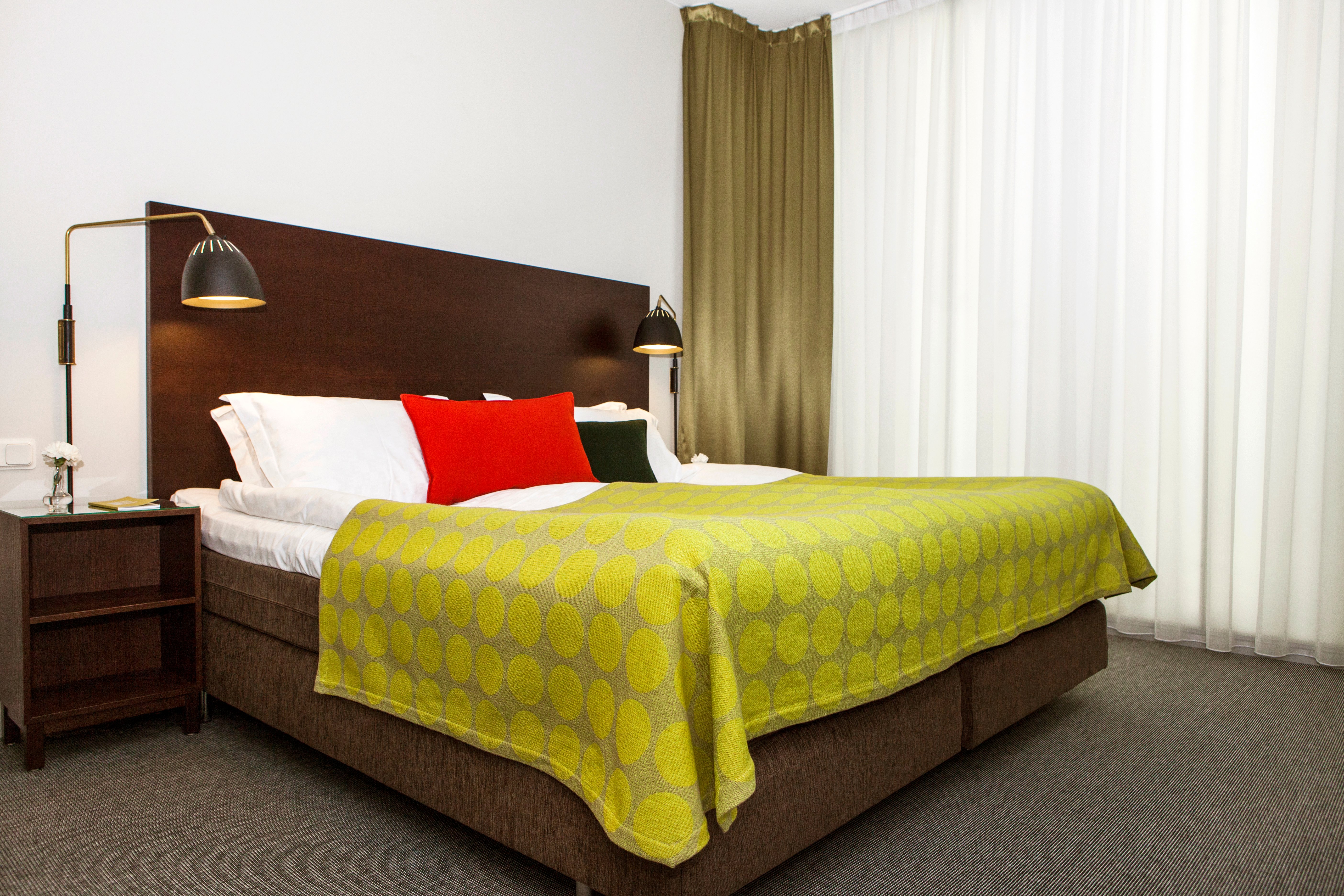 Hotellrum med säng, stor sänggavel och sänglampor