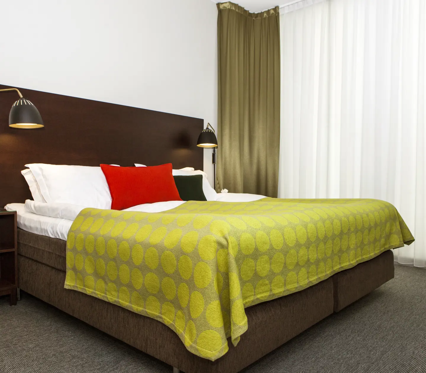 Hotel room with bed, large headboard and bedside lamps