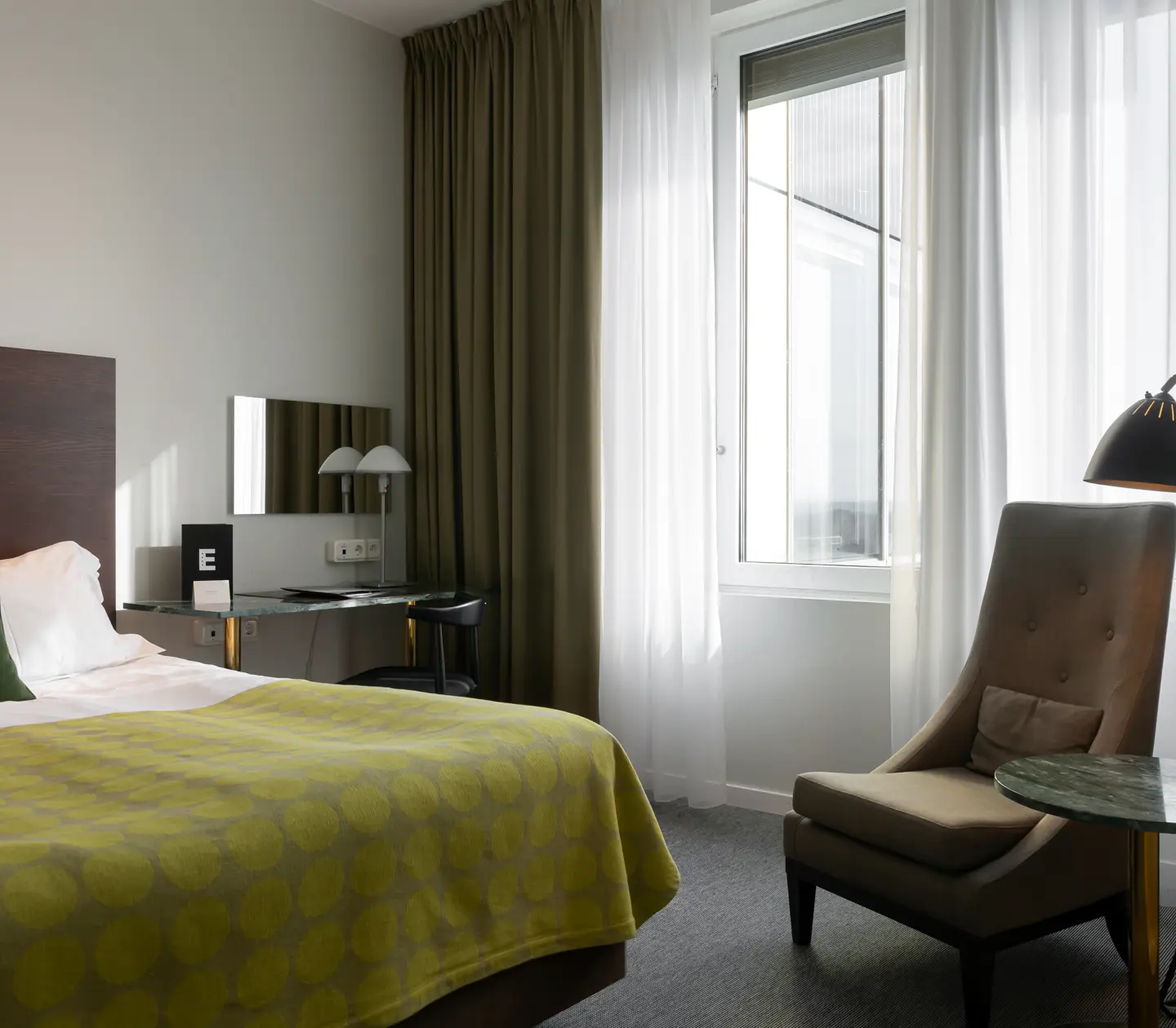 Bright hotel room with bed, armchair and balcony door