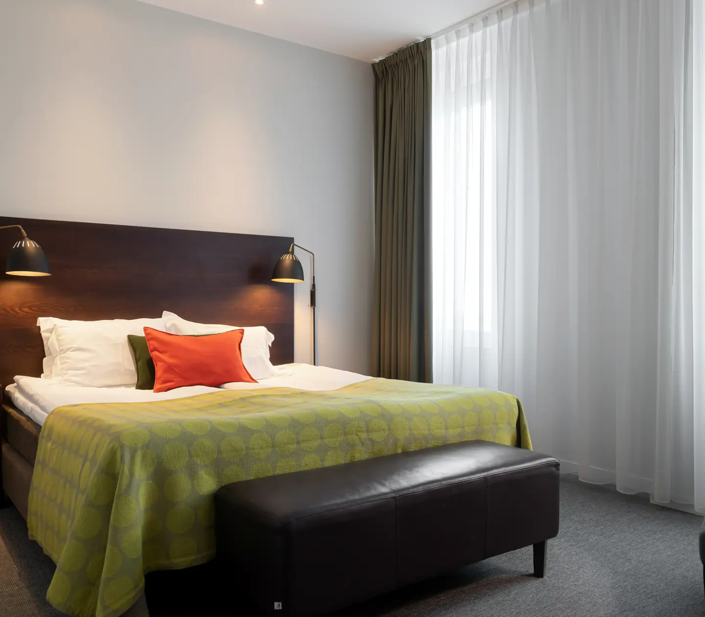 Bright hotel room with bed, armchair and window