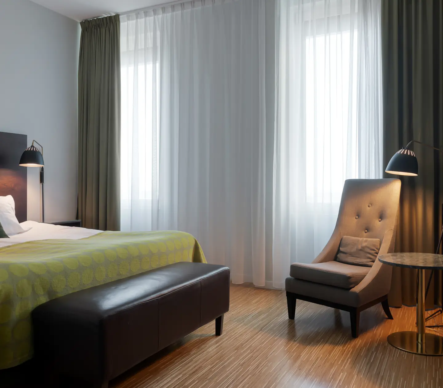 Bright hotel room with bed, armchair and window
