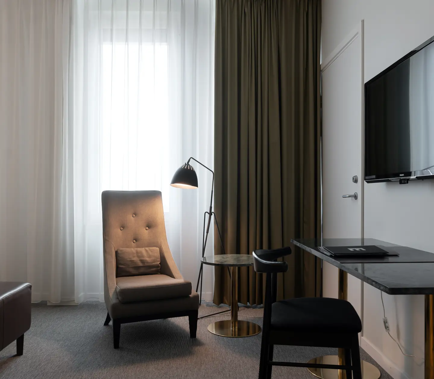 Bright hotel room with desk, armchair and window