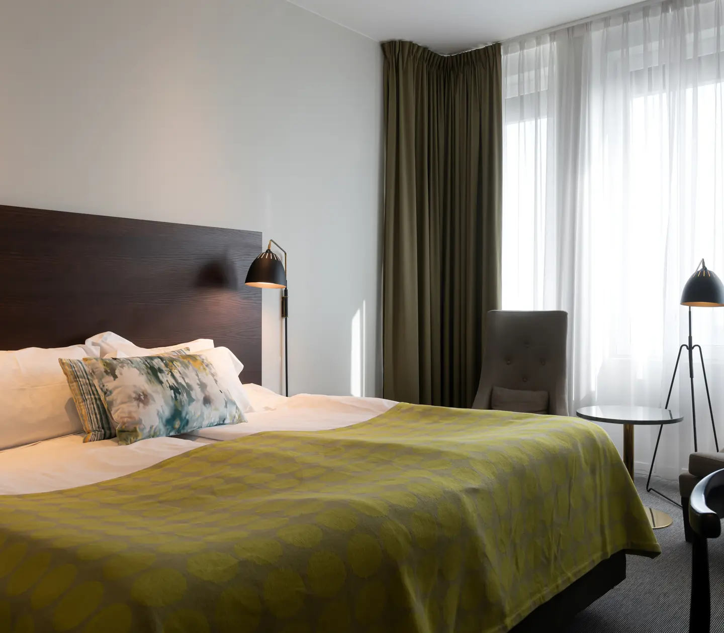 Bright hotel room with bed, armchairs and window