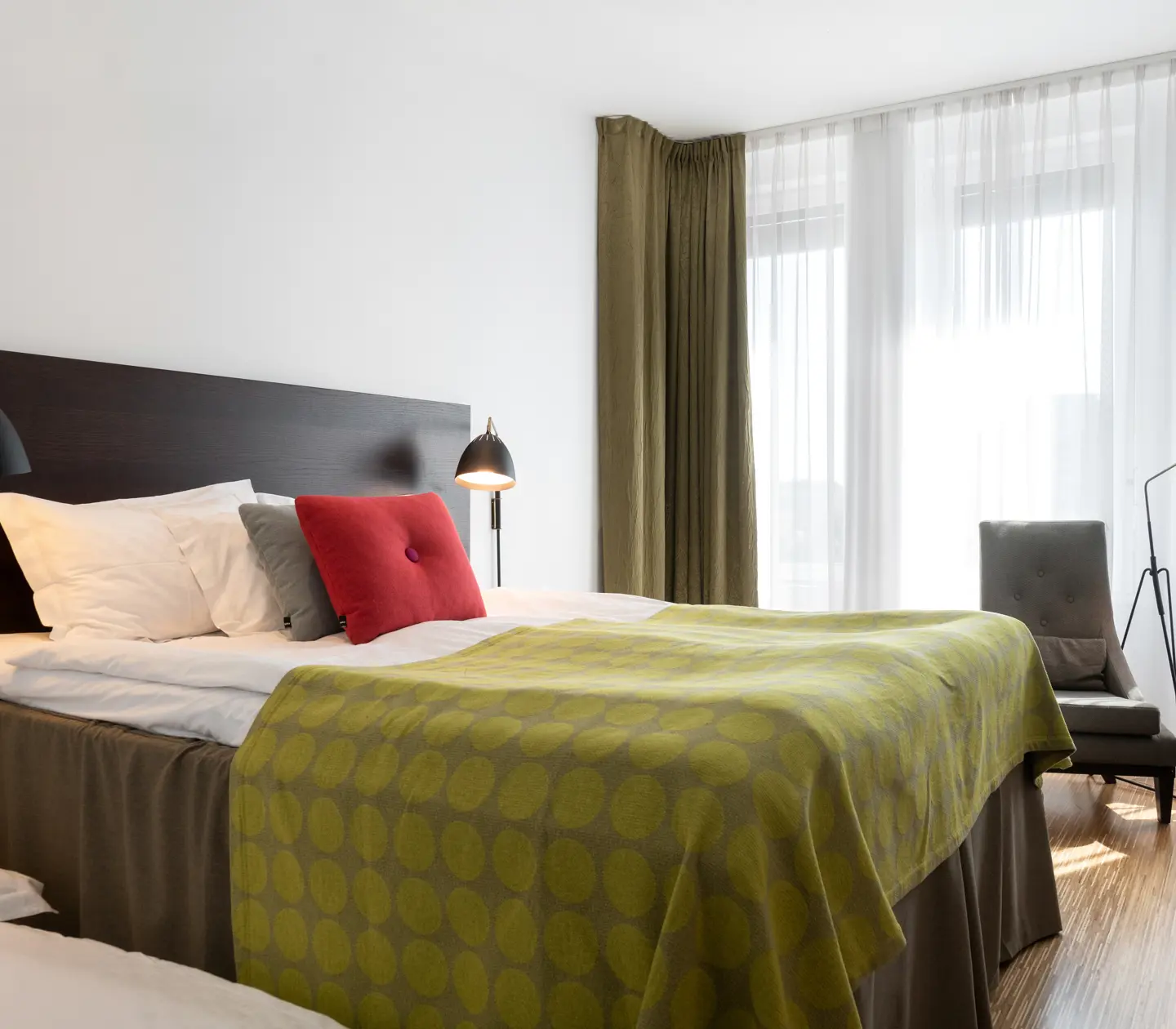 Bright hotel room with bed, armchairs and window