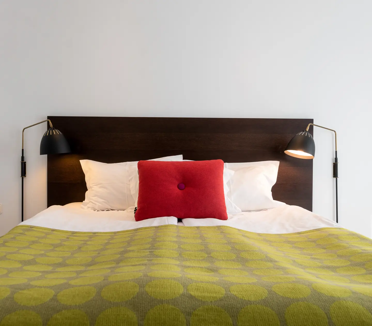 Bright hotel room with bed, red pillow and bedside lamps