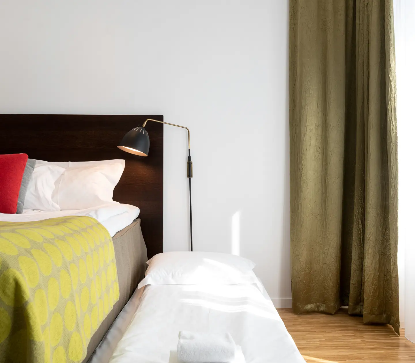 Bright hotel room with bed, extra bed and bedside lamp
