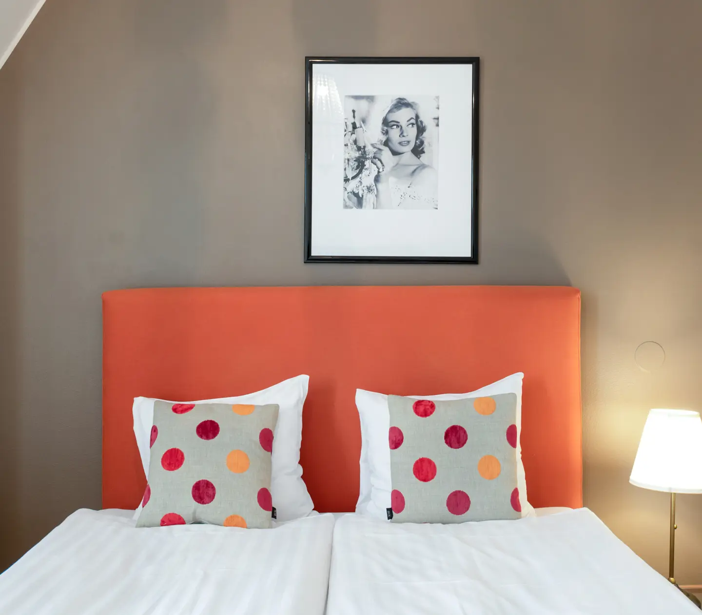 Bright hotel room with bed, orange headboard and blackboard