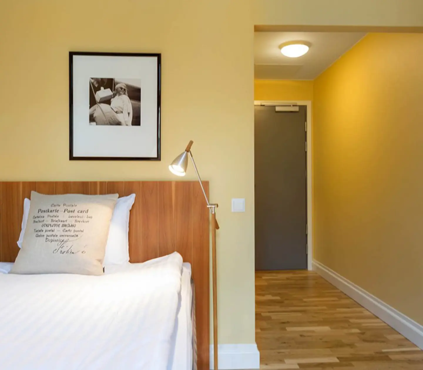 Yellow hotel room with bed, wooden headboard and painting
