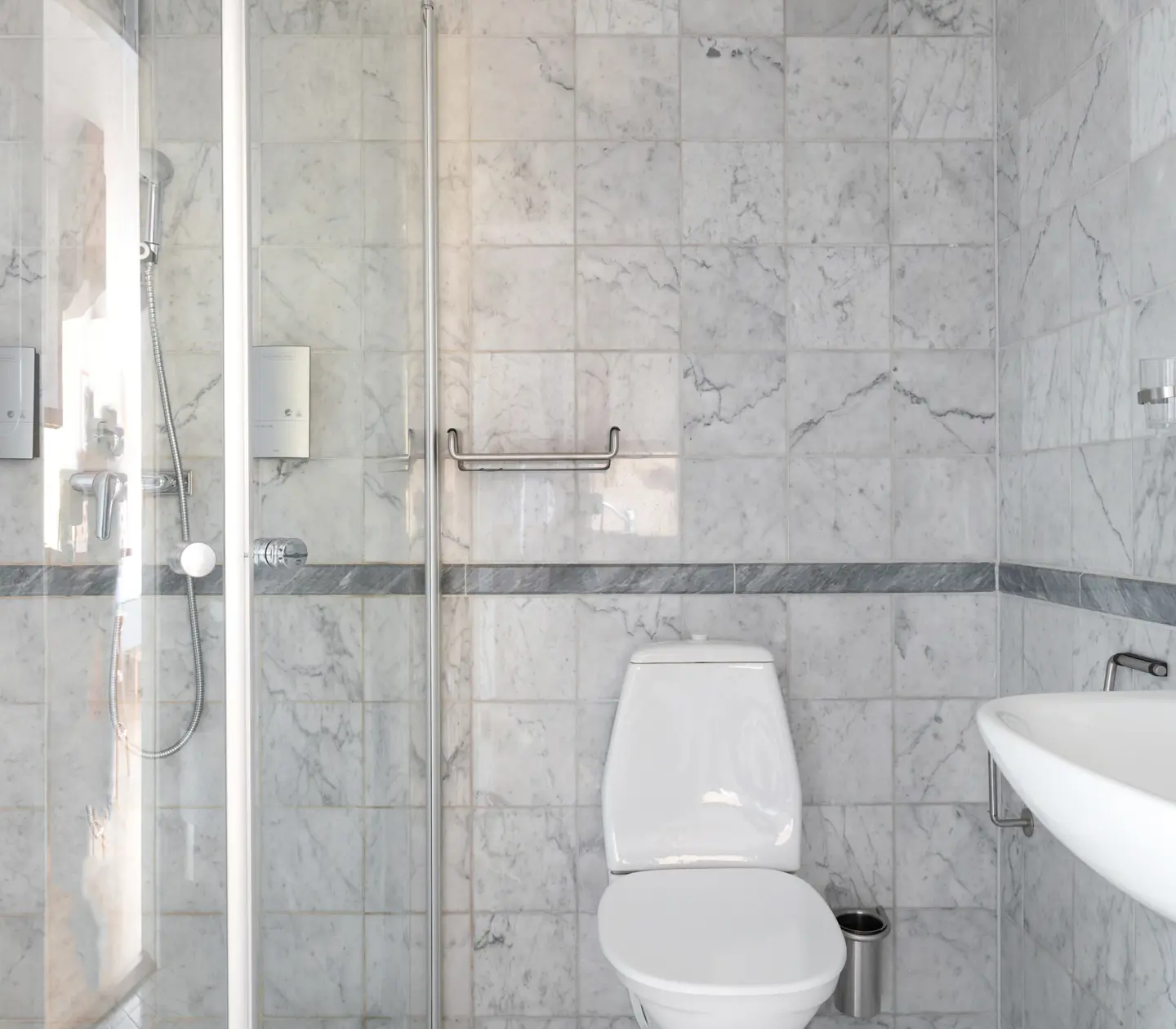 Bright marble bathroom with shower, toilet and sink