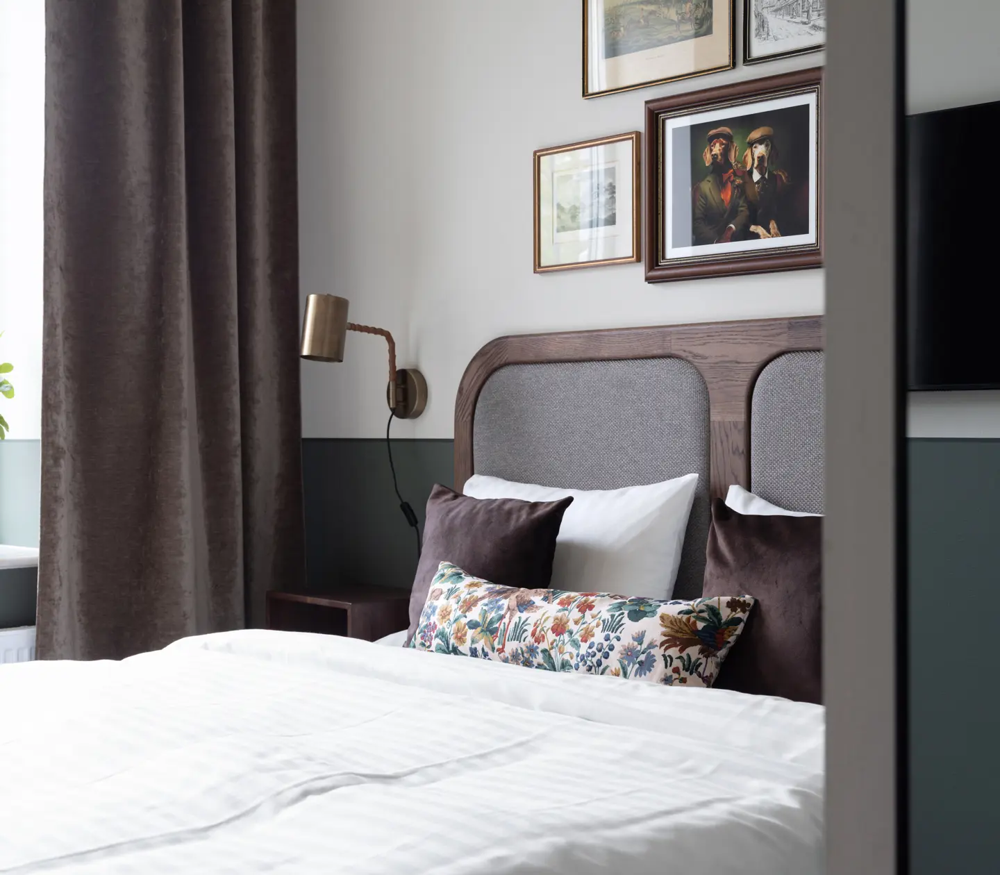 Ljust hotellrum med säng, skrivbord och tavla