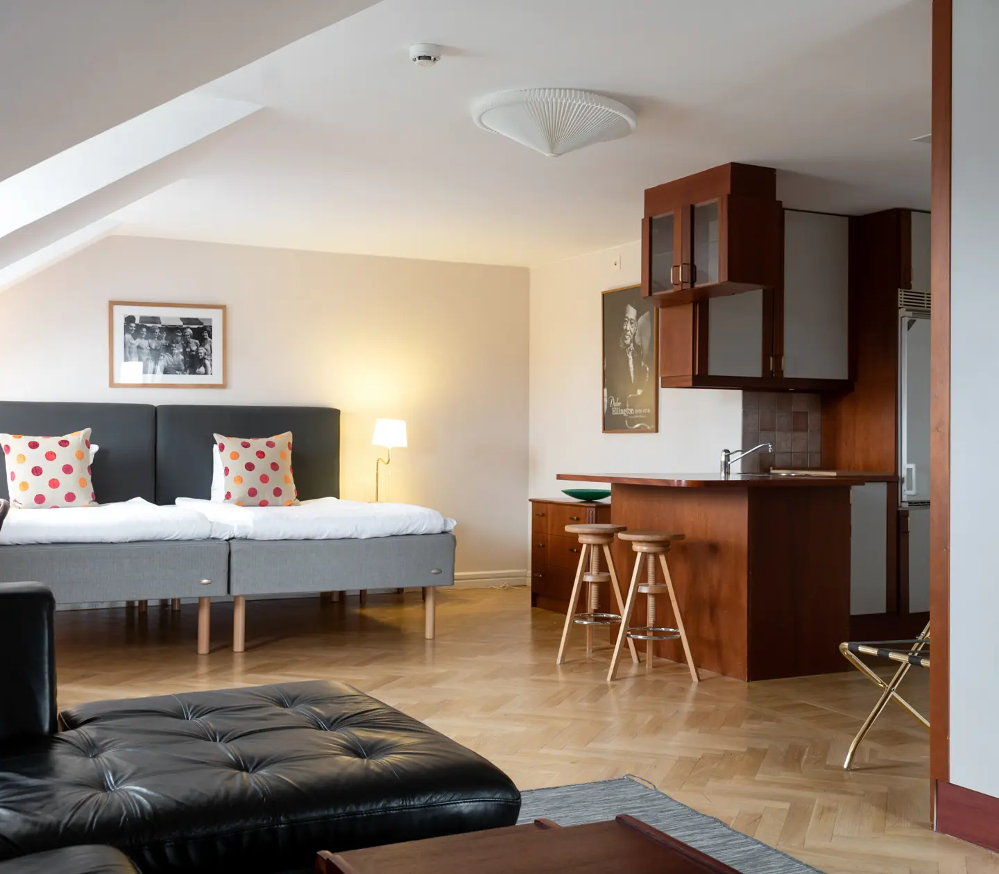 Hotel room with beds, black sofa and kitchen