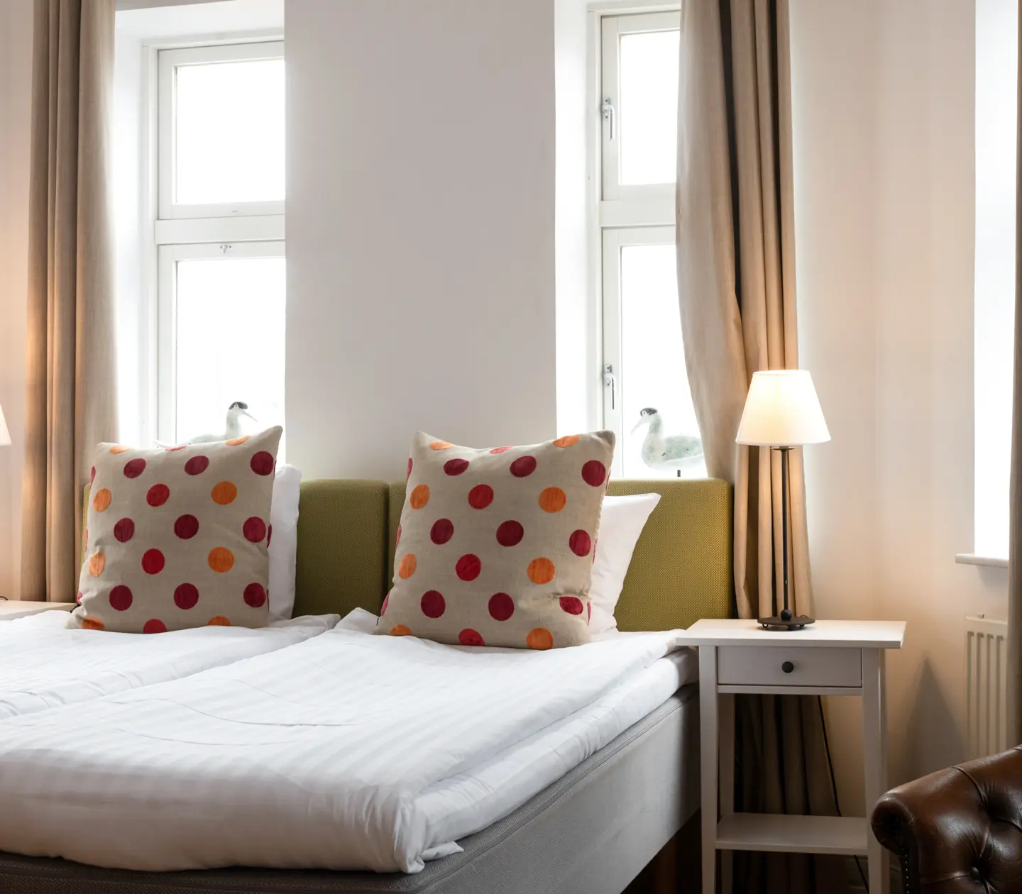 Cozy hotel room with bed, green headboard and bedside lamps