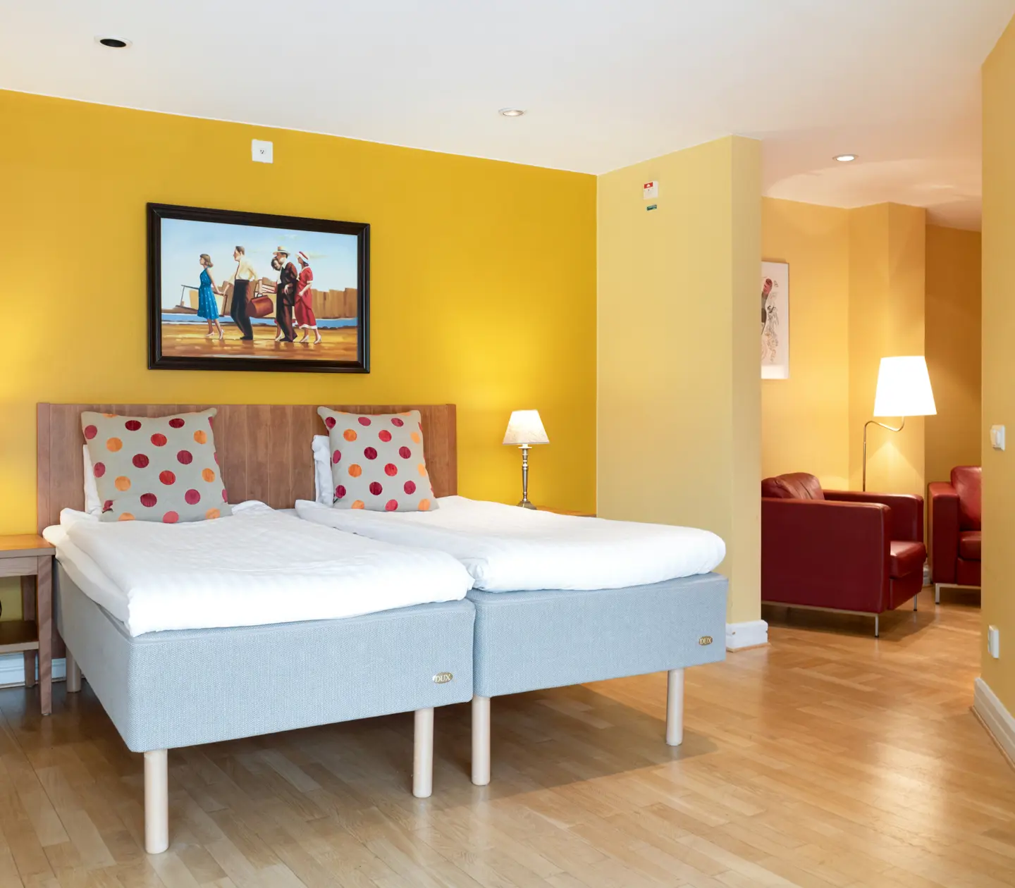 Yellow hotel room with bed, wooden headboard and painting