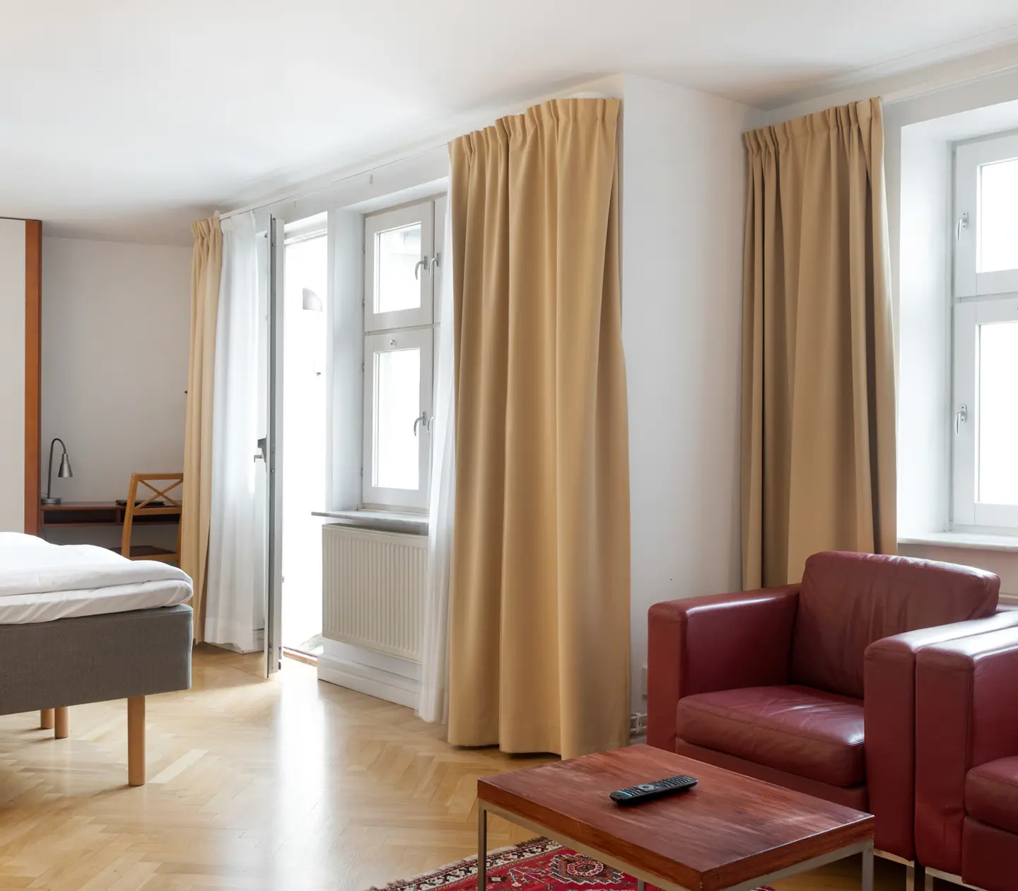 Bright hotel room with red leather armchairs, window and wardrobe