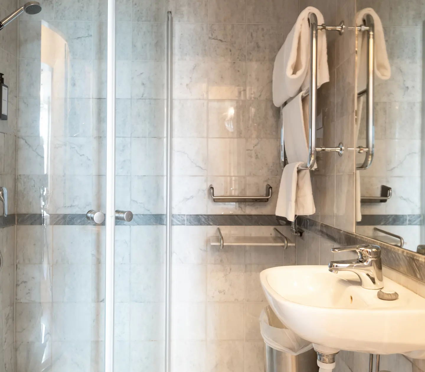 Bright marble bathroom with shower, towels and sink