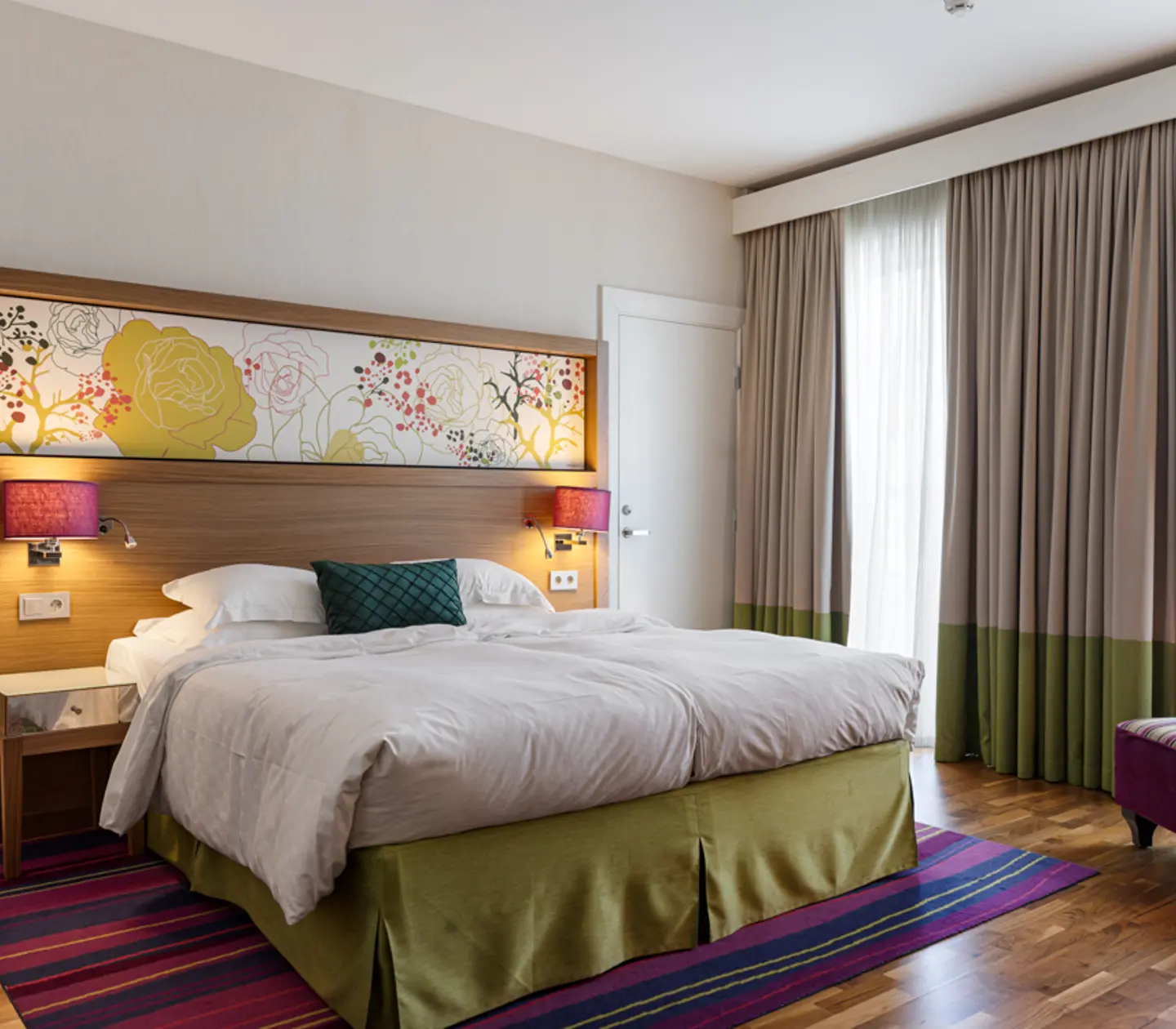 Stort hotellrum med dubbelsäng, fåtölj och fönster