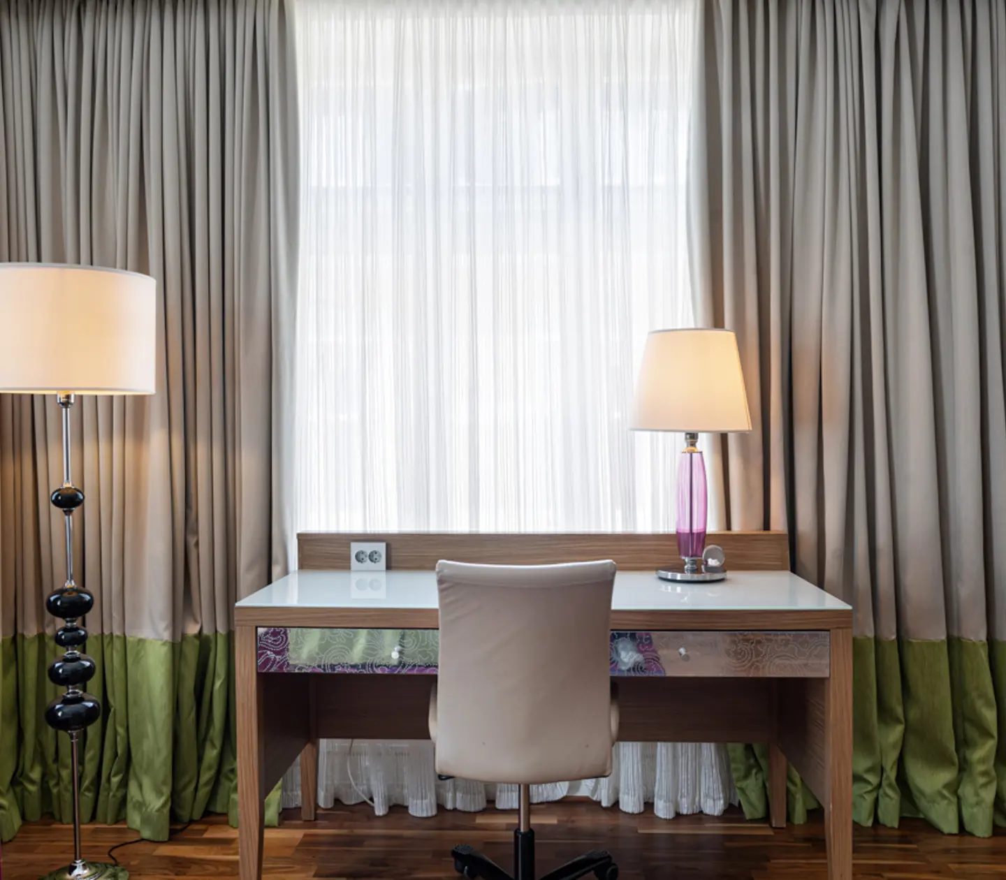 Hotellrum med fåtölj, skrivbord och fönster