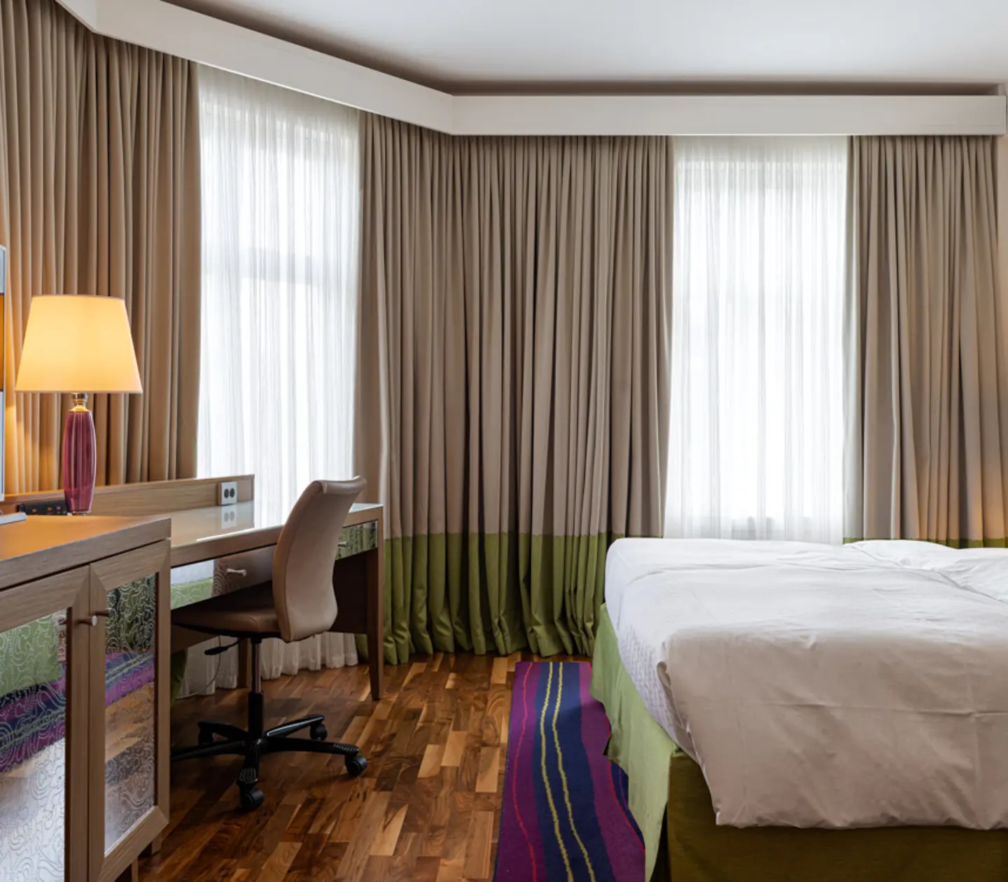 Hotellrum med dubbelsäng, fåtöljer och skrivbord