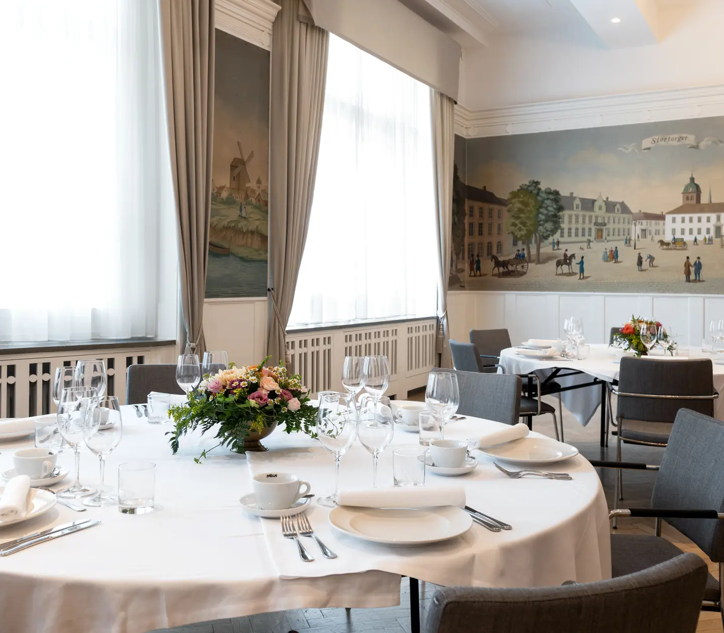 Room with fine paintings and set round tables