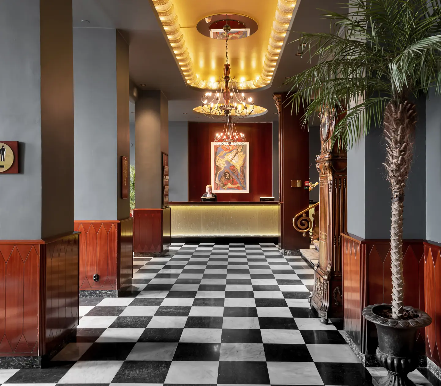 Hotel lobby with reception desk, checkered floor and palm tree
