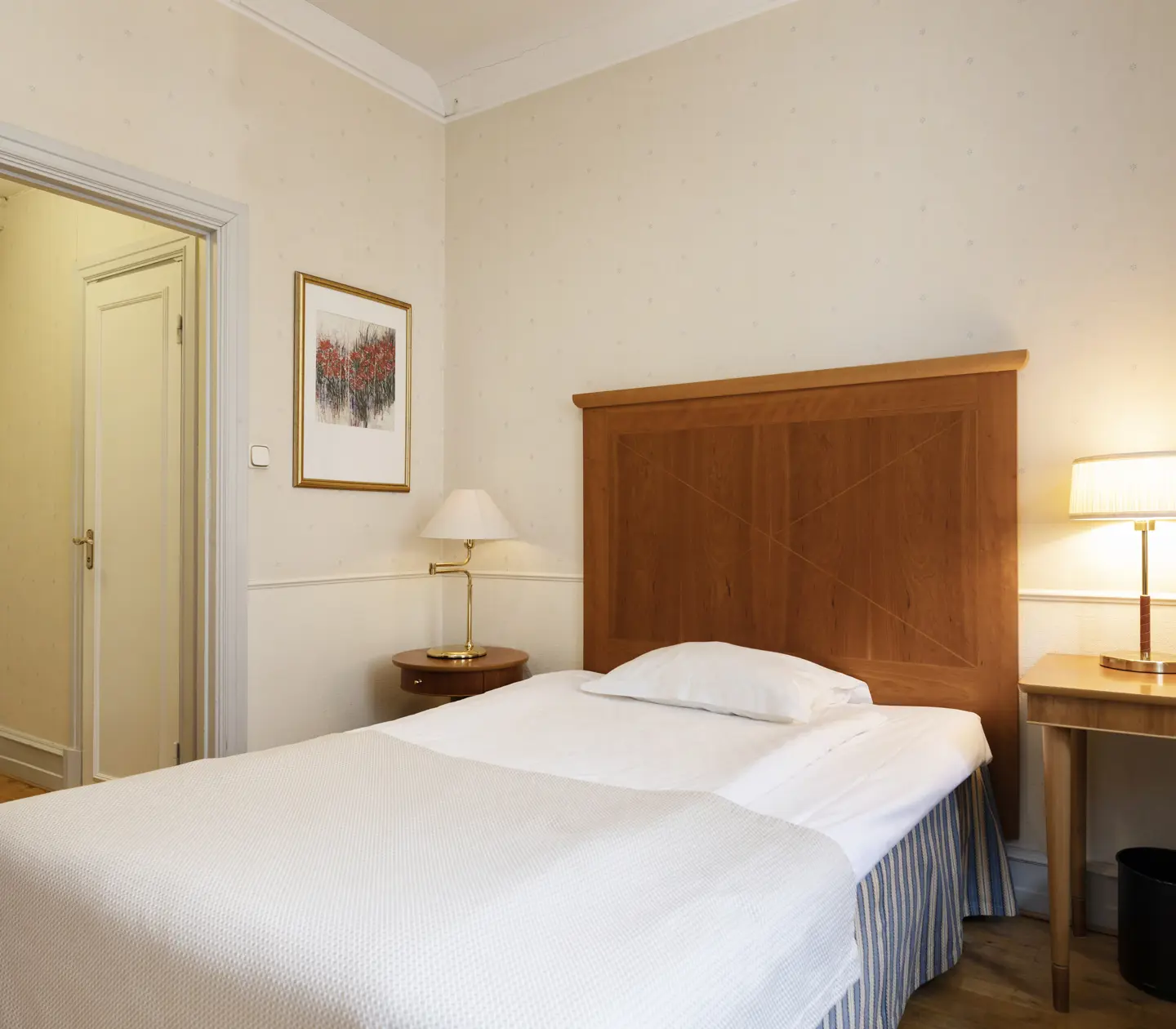 Hotel room with single bed, desk and table lamps