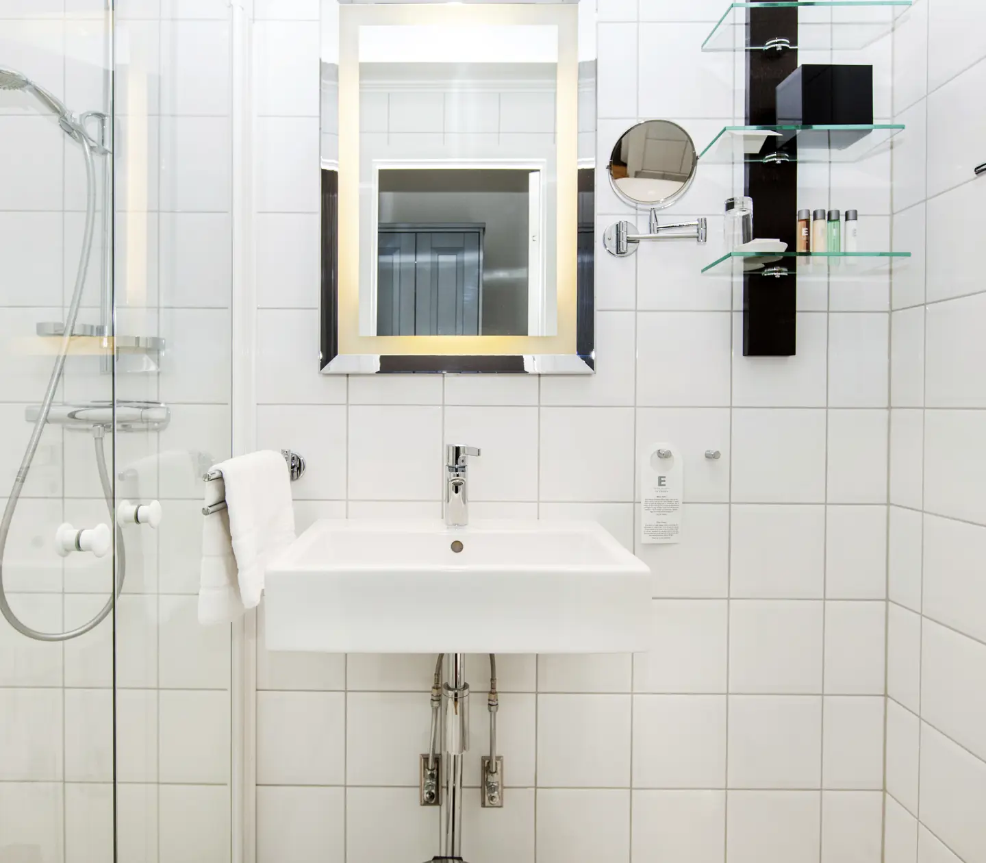 White bathroom with toilet, sink, mirror and shower