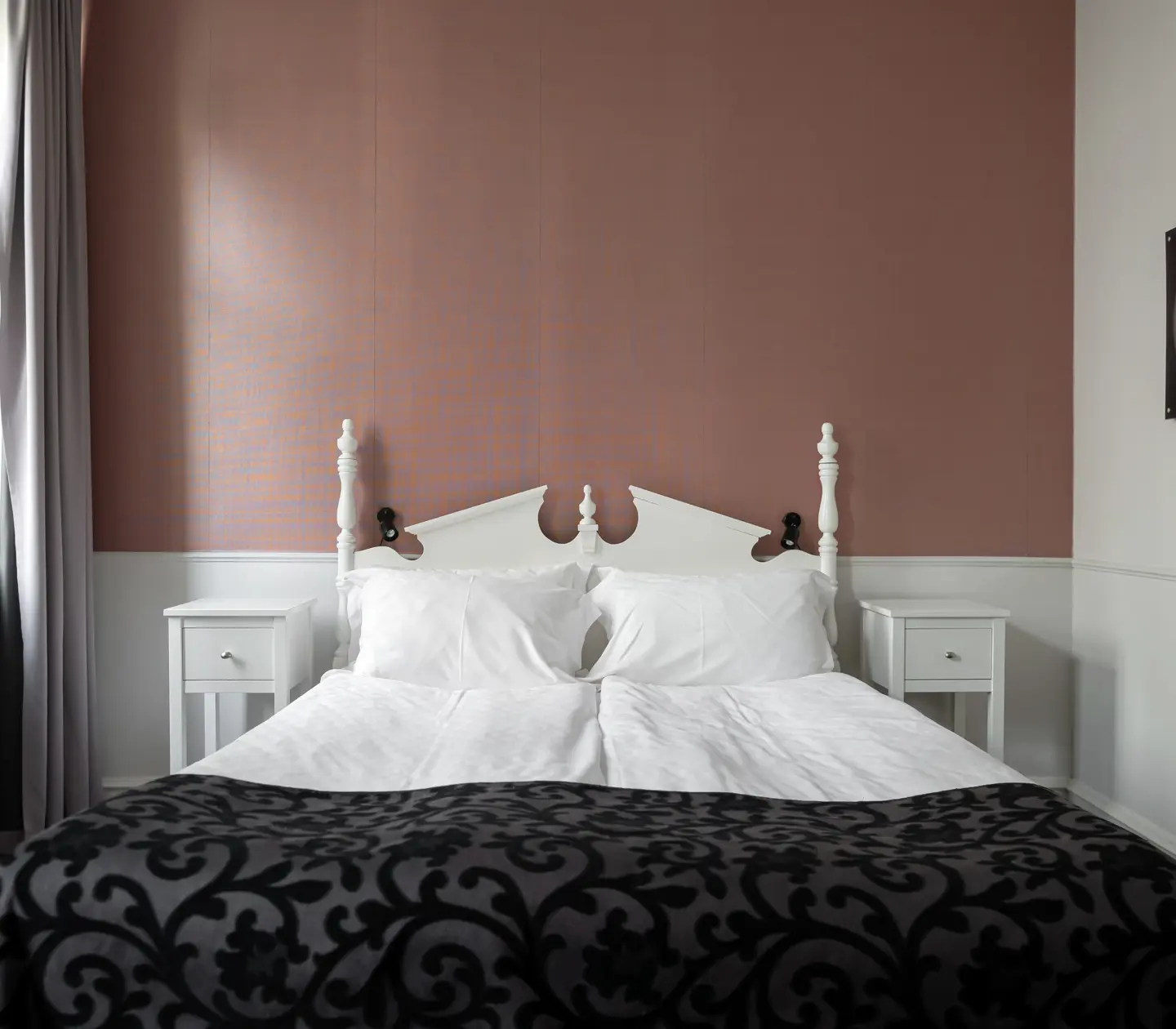 Hotel room with pink wallpaper, double bed and bedside table