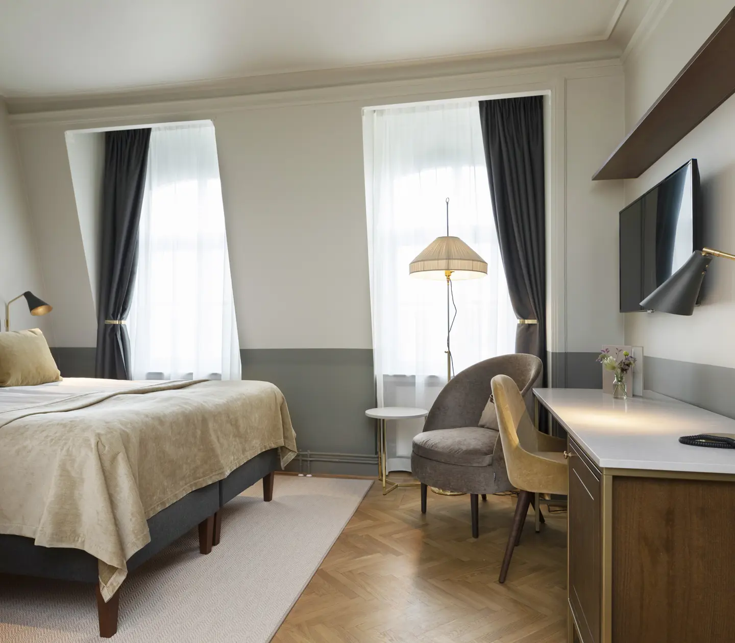 Bright hotel room with double bed, desk, armchair and window