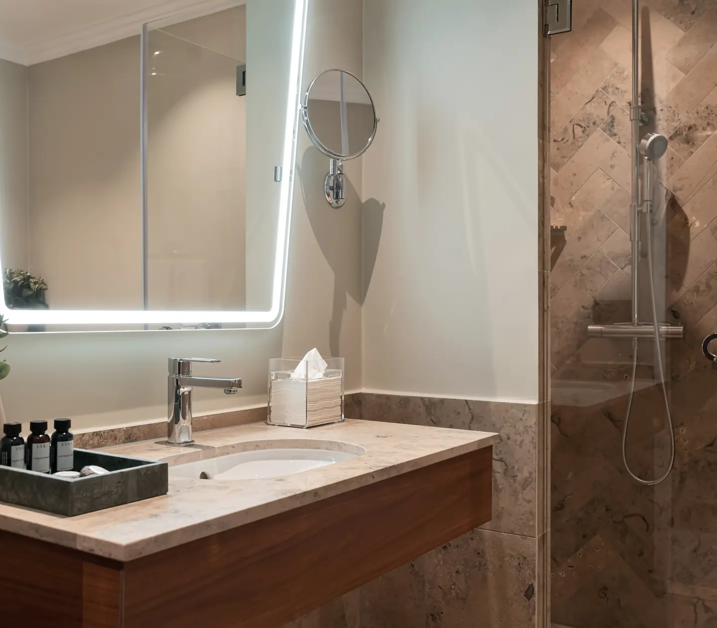 Beige bathroom with shower, sink and mirror