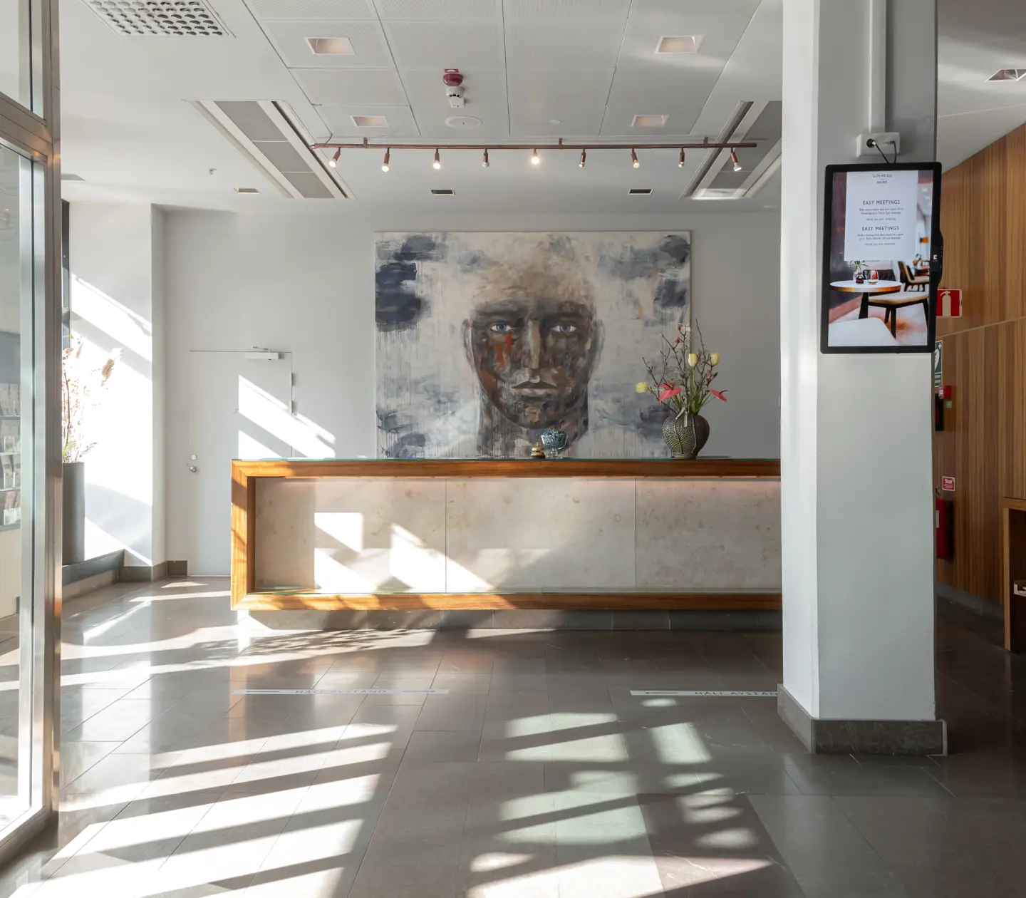 Hotel lobby with reception desk and large face painting