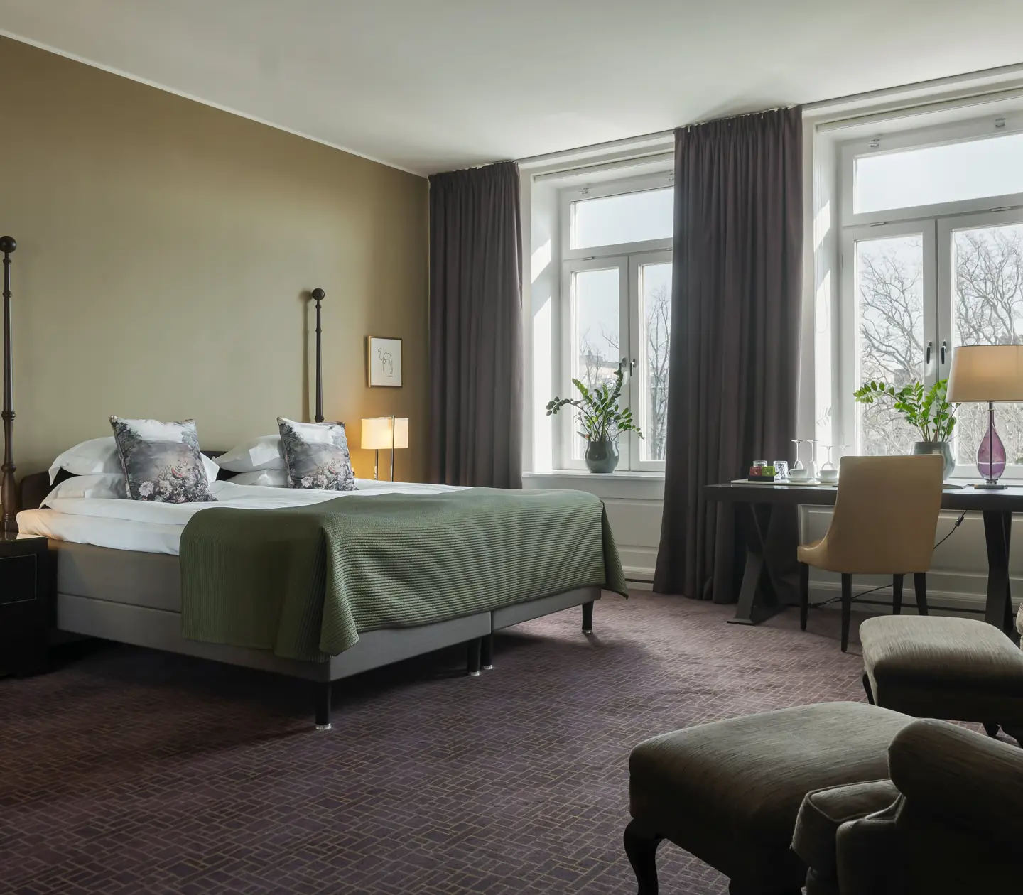 Hotel room with large bed, armchairs, desk and window
