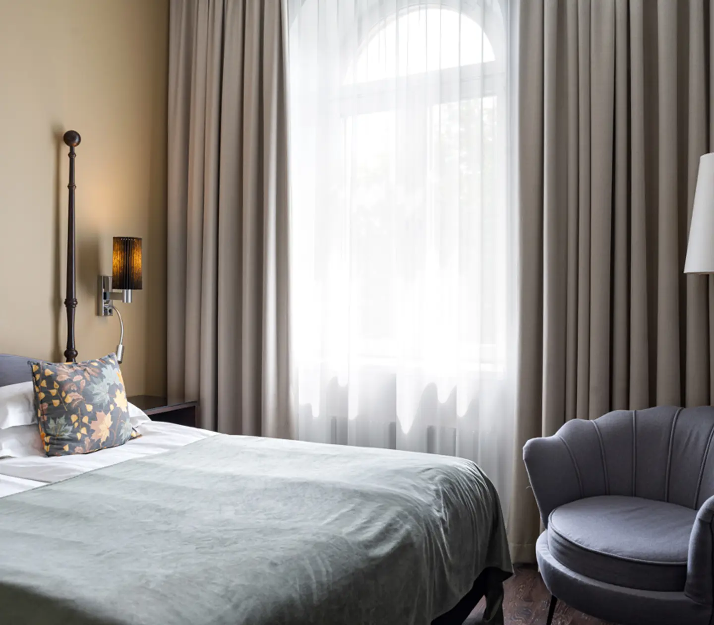 Bright hotel room with bed, armchair and window
